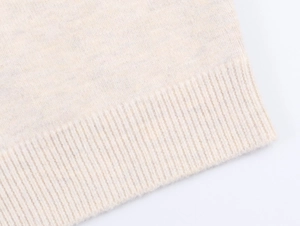 Close-up of beige knit cardigan showing fine ribbed hem detail and soft texture