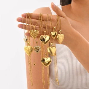 Various gold heart-shaped locket necklaces with patterns and crystals on a white background