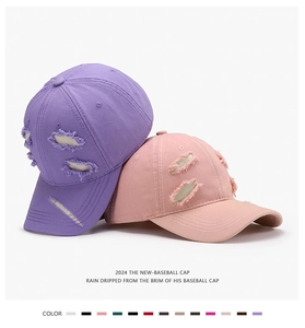 Close-up of distressed vintage baseball caps in lavender and pink with ripped brim details