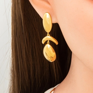 Close-up of elegant gold leaf-shaped teardrop earrings worn by a model with long hair