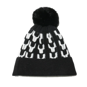 Detailed close-up of knit texture and black pompom on the black and white winter beanie