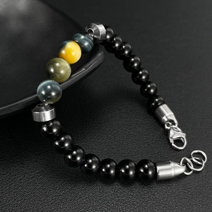 Men's stainless steel bracelet with natural tiger eye and black beads on textured background
