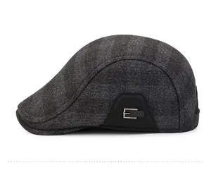 Detail of dark grey woven winter newsboy hat with ear protection and metal E-logo decor