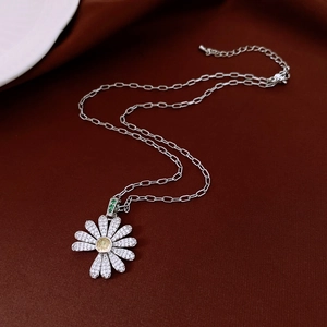 Macro detail of daisy flower pendant with inlaid zirconias on red velvet background