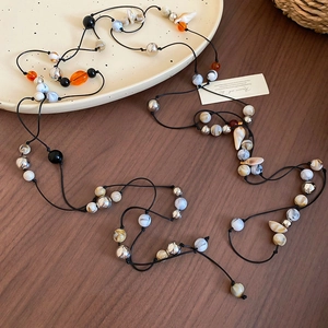Detailed view of bohemian waist chain with acrylic beads and shell pendants on wood