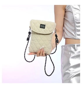 Detail of beige quilted crossbody phone bag with black Fashion label and adjustable cord strap