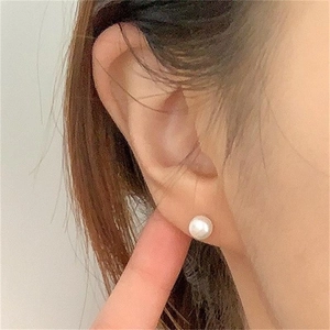 Close-up of a white freshwater pearl stud earring worn by a model on the earlobe