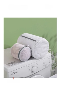Detail of cylindrical mesh laundry bags with grey zippers on a white washing machine