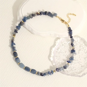 Detailed shot of irregular blue stone necklace with golden cube beads and metal clasp
