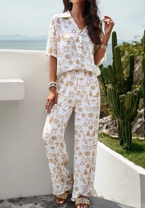 Detail of white two-piece vacation set with golden shell and palm tree print patterns