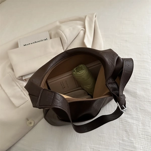 Deep brown leather tote bag showing large capacity for umbrella and books in flat lay view