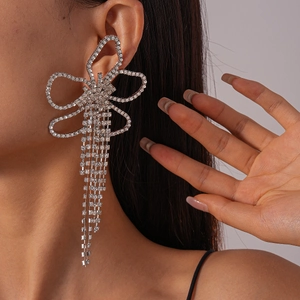 Macro shot of silver crystal bow earrings with long sparkling rhinestone tassels on model