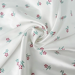 Detailed macro view of white floral satin fabric with red flowers and smooth texture