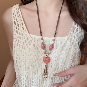 Détail du pendentif cœur en céramique rose avec gland tressé sur un collier folklorique