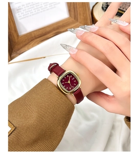 Gros plan d'une montre vintage dorée pour femme avec bracelet en cuir rouge vin