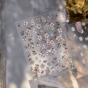 Macro shot of jelly nail stickers with pink flowers, red berries and gold outlines