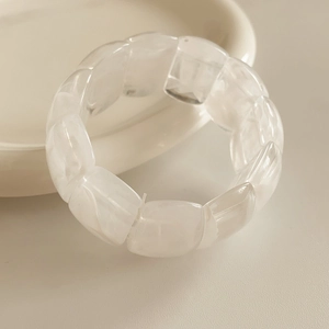 Detailed view of cream acrylic beaded elastic bracelet on a ceramic plate edge