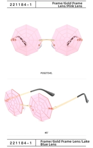 Detail view of pink rimless octagonal sunglasses with spider web pattern and gold temples