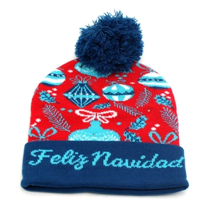 Detail of Feliz Navidad knit hat featuring festive Christmas ball patterns and blue pompom