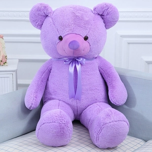 Detail of a large purple teddy bear plush toy with ribbon bow on a cozy sofa