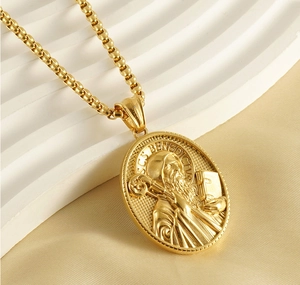 Macro shot of gold-plated Saint Benedict religious relief pendant on stainless steel chain