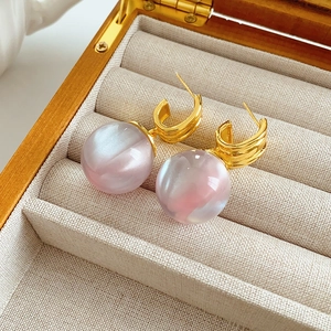 Macro shot of irregular pink resin pearl earrings in a luxury jewelry display box