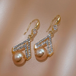 Close-up of V-shaped gold earrings with sparkling crystals and champagne pearls on silk