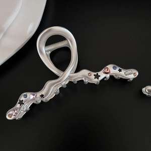 Macro detail of matte silver shark clip with colorful star and heart-shaped zircons