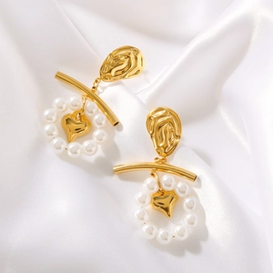 Vintage gold heart earrings with white pearls on elegant white silk fabric background