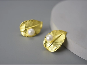 Detailed macro view of S925 silver leaf stud earring with pearl inlay and golden finish