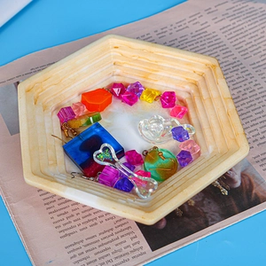 Macro detail of colorful resin jewelry charms in a hexagonal marble pattern tray