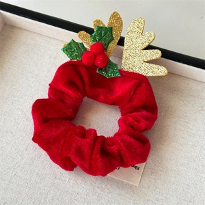 Détail d'un chouchou de Noël en velours rouge avec bois dorés pailletés et houx festif