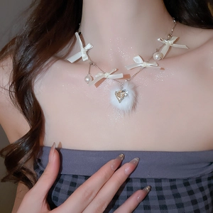 Close-up of pearl necklace with white ribbon bows and a fluffy white faux fur heart pendant
