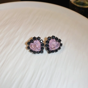 Macro view of heart-shaped pink crystal earrings with black gemstone accents