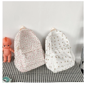 Detail shot of two canvas backpacks with distinct floral patterns on a checkered mat
