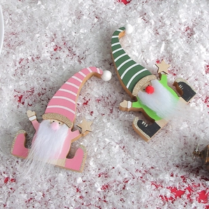 Handcrafted wooden Christmas gnome ornaments with striped hats and stars on snow background
