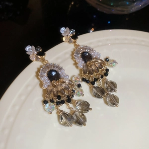 Dettaglio degli orecchini vintage con fiori, gemme nere e nappe di perline colorate
