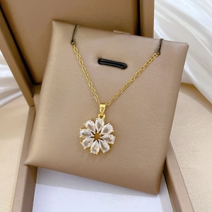 Détail d'un collier fleur rotatif doré serti de cristaux brillants dans un coffret