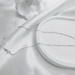 Detailed view of S925 sterling silver ball chain with lobster clasp on silk fabric
