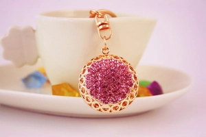 Close-up of golden keychain featuring a spherical pendant with dense pink rhinestones