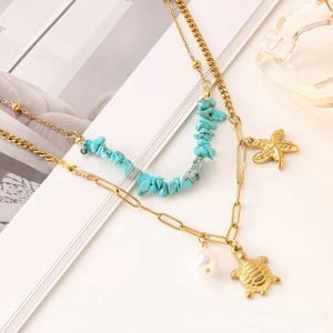 Detail of layered turquoise necklace with gold starfish, turtle charms and white pearls