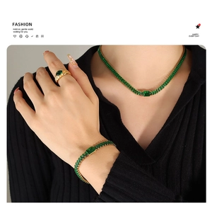 Dettaglio del set collana e bracciale in oro con zirconi verdi su una modella