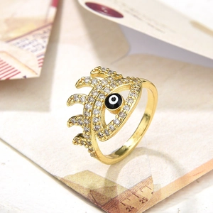 Golden evil eye open ring with black enamel and zircons on a decorative background