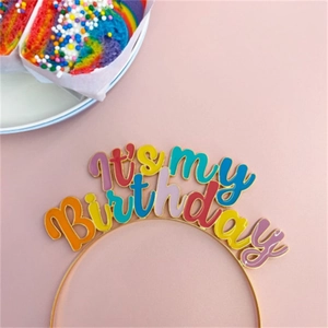 Close-up of colorful It's my Birthday headband with enamel letters on pink background