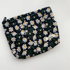 Detailed close-up of daisy floral embroidery on black canvas cosmetic storage pouch