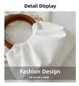 Close-up of white pleated cloud bag showing wooden round handle and metal hardware hooks