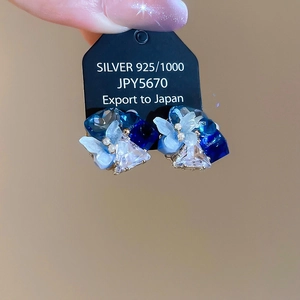 Detailed macro shot of S925 silver flower earrings with blue crystals and pearls