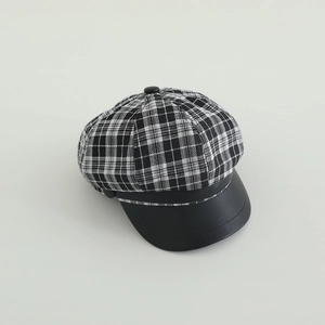 Close-up of black and white plaid texture with matte leather brim on newsboy hat