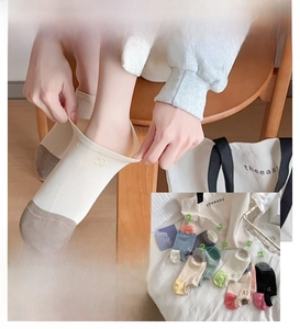 Detail of color-blocked low cut socks featuring a small smile embroidery on the ankle