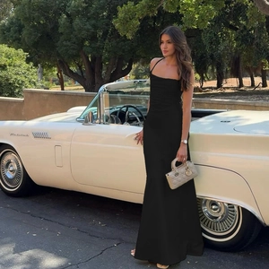Robe longue noire moulante à fines bretelles devant une voiture de collection décapotable